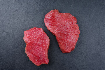 Raw dry aged bison beef rump steaks offered as top view on black background with copy space