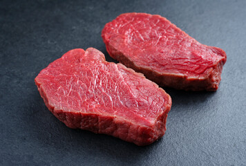 Raw dry aged bison beef rump steaks offered as close-up on black background with copy space