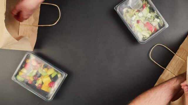 Packaging take away meals into paper bags top view, Food delivery in disposable containers, catering, balanced nutrition. Fresh cooked portions in lunch boxes, vegetarian dishes. Healthy eating.