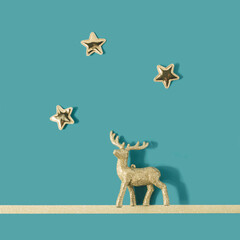 Reindeer Christmas tree ornament with golden stars above on a pastel blue background. Holiday celebration concept.