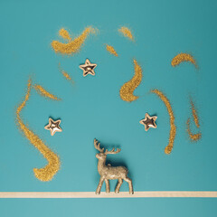 Golden reindeer ornament on a pastel blue background with glittering stars above. Minimal Christmas concept