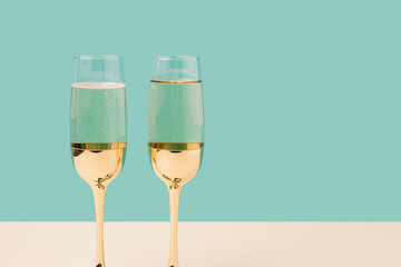 Romantic champagne glasses set up on a turquoise background. Minimal Valentines concept