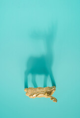 Reindeer ornament shadow on a light turquoise background. Minimal Christmas concept