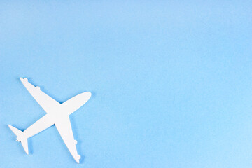 Top view flat lay of white plane model on light sky blue background with copy space.