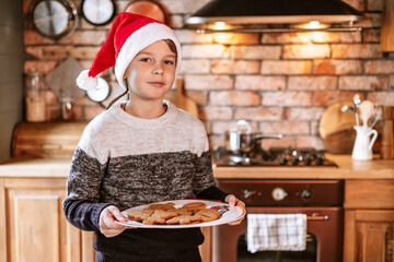 cute kid boy in Santa hat in kitchen chalet decorated for celebration Christmas and New Year eve are cooking gingerbread, smiling and having fun