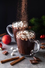 Dripping powder on glass mug with hot chocolate cocoa drink with marshmallow. Copy space. Dark...