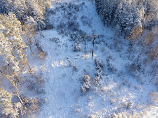 Overhead power line, electrical wiring, surrounded by trees during the winter. Aerial view...