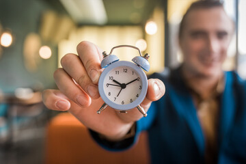 The hand of a smiling businessman man holds the alarm clock. The Concept of Time