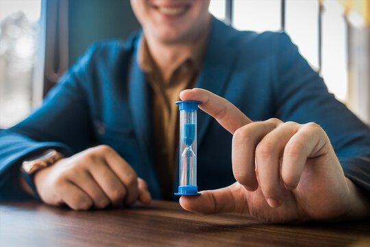 Businessman's hand holds hourglass clock timer, close-up