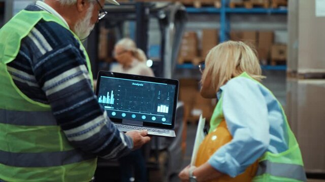Workers holding Laptop screen with business charts in warehouse - Powered by Adobe