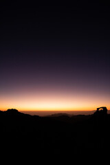 sunset on a mountaintop with silhouettes on the horizon