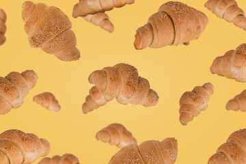 Freshly baked croissants flying in the air isolated on a bright yellow background.