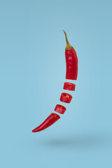 Sliced red hot chili pepper floating in air isolated on blue background.