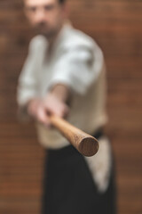 A man keep in hand a wooden weapon jo straight with selective focus on jo