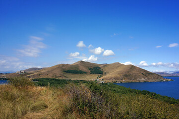 Obraz premium a hill surrounded by the water of Lake Sevan in Armenia in summer in sunny weather