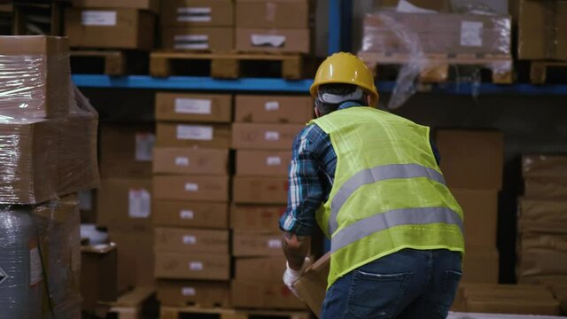 Slow motion shot of a male worker stacking cardboard boxes in a warehouse