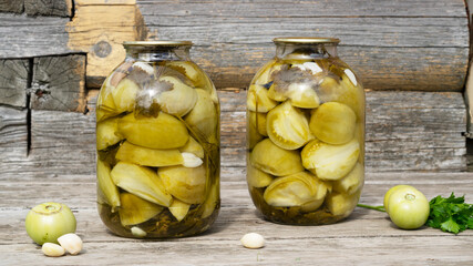 Fermented tomatoes for winter. Homemade pickled green tomatoes in a glass jars with garlic and...