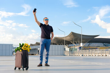 Young man with luggage meets passengers at the airport. Vacation concept