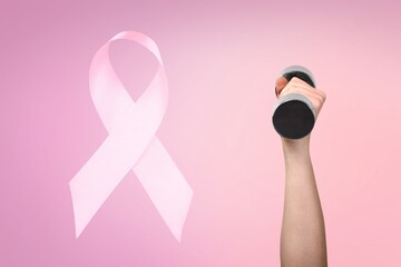 First person raised woman's hand holding a dumbbell and pink ribbon, symbol of breast cancer...