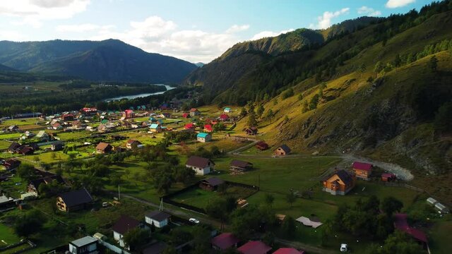 Bird's-eye view of the Altai village of Chemal in a green mountain valley with a river. Rural summer landscape in the Altai Republic, Russia