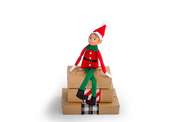 Christmas Elf  sitting on a stack of gift boxes on an isolated  white background with copy space. Christmas spirit, Christmas family tradition.
