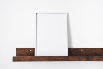 Mock up scene with empty poster frame on shelf. Copy space
