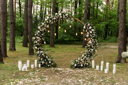 Blooming decoration of wedding arch with roses, carnation and eucalyptus. Beautiful wedding ceremony outdoors. White and pink colors. Wedding photo zone. Floral concept. Wedding details