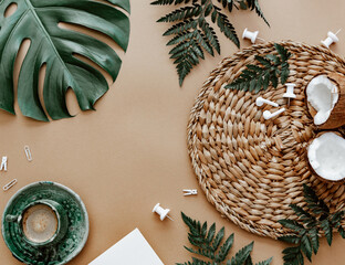 Natural flat lay with coffee cup, coconut, green monstera leaf on brown background. Space for text, blogger background, neutral colors, workspace - 473410915