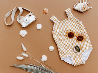 Flat lay retro vintage swimsuit for baby girl on brown background. Minimal summer concept