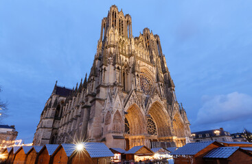 Cathedral of Notre Dame, Reims and Christmas market stalls in the night. One of the most stunning masterpieces of 13th century Gothic art. - obrazy, fototapety, plakaty
