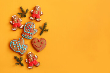 Festive banner: gingerbread in the form of men, hearts, mittens with fir branches on a yellow background, top view, place for text