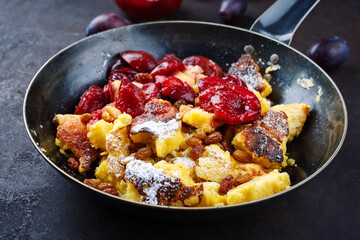 Traditioneller österreichisch Kaiserschmarren mit Zwetschgen und Rosinen serviert als close-up in einer rustikalen Bratpfanne 