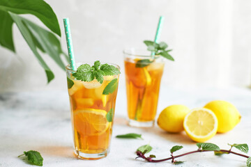Iced iced tea in a glass with a straw, mint leaf and lemon slices inside. Cool drinks in the heat