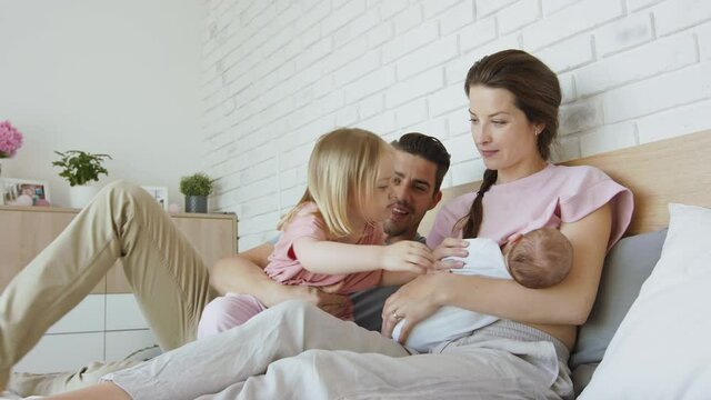 Happy young family with newborn baby and little girl enjoying time together at home.