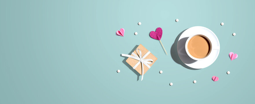 A cup of coffee with a gift box and hearts - flat lay