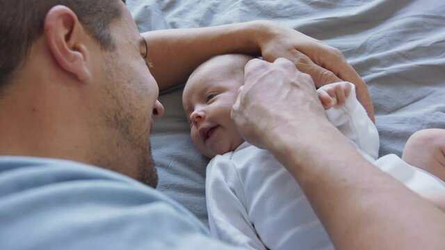 Close up of young father enjoying time together with newborn baby girl at home.