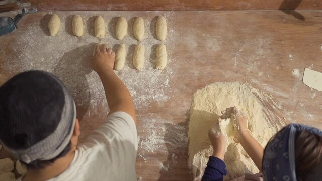 Man sprinkling flour on a mass of bread