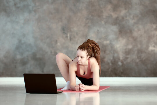 Online yoga lessons in gym, woman watches training videos and repeats pose.