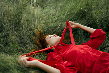 pretty woman in red dress lies on the grass in the field nature fresh air