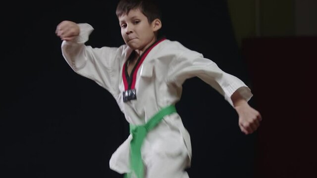 A little boy doing martial arts - jumping on the spot and showing a kick from the turn