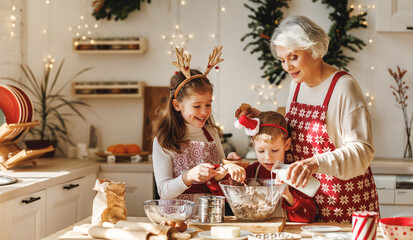 Two little kids making Christmas homemade cookies together with elderly grandmother in kitchen - obrazy, fototapety, plakaty