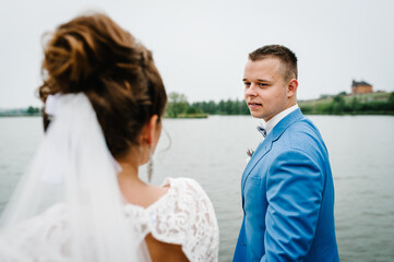 Fototapeta premium The groom looks at the bride in nature near the lake.