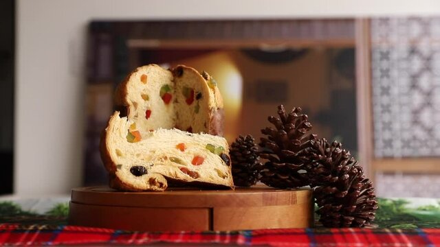 camera approaching a panettone on the table, decorated with pine cones and Christmas ornaments. Traditional panettone. panettone with candied fruit on the table