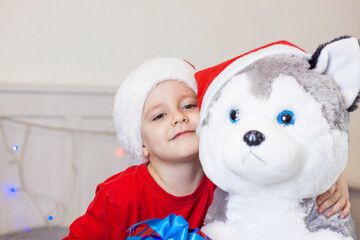 Portrait of a cute boy in a Santa Claus hat. Funny smiling child. Gifts, toys, joy, celebration.