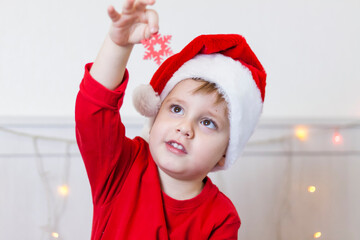 Portrait of a cute boy in a Santa Claus hat. Funny smiling child. Gifts, toys, joy, celebration.