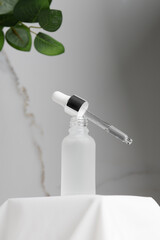 White serum bottle with pipette on  podium. Natural skincare cosmetic