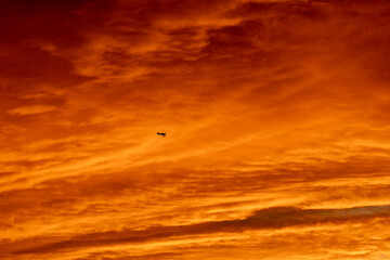 Golden sunset with airplane silhouette in front of clouds