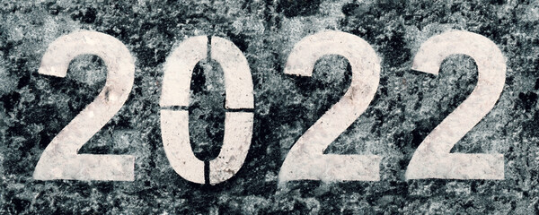 Numbers 2022 painted on pavement covered with melted snow in thawing winter weather