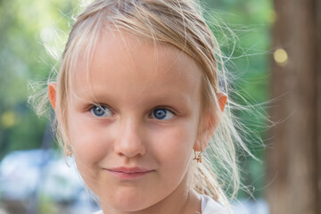 little adorable cute girl 6-7 years old, with blond hair, and piercing blue eyes, portrait of a child with a sly look