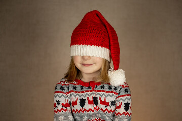 girl in santa hat and New Year's pajamas on a solid background. hat closes eyes